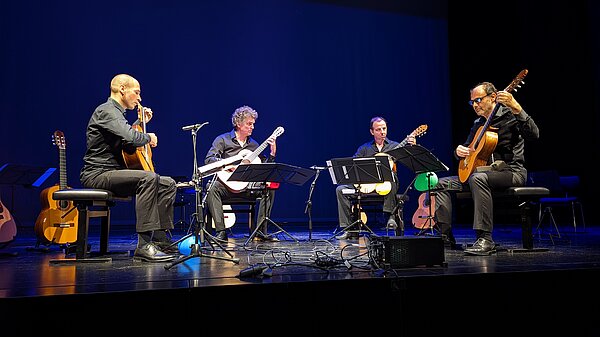 Vier Gitarrenspieler auf einer Bühne